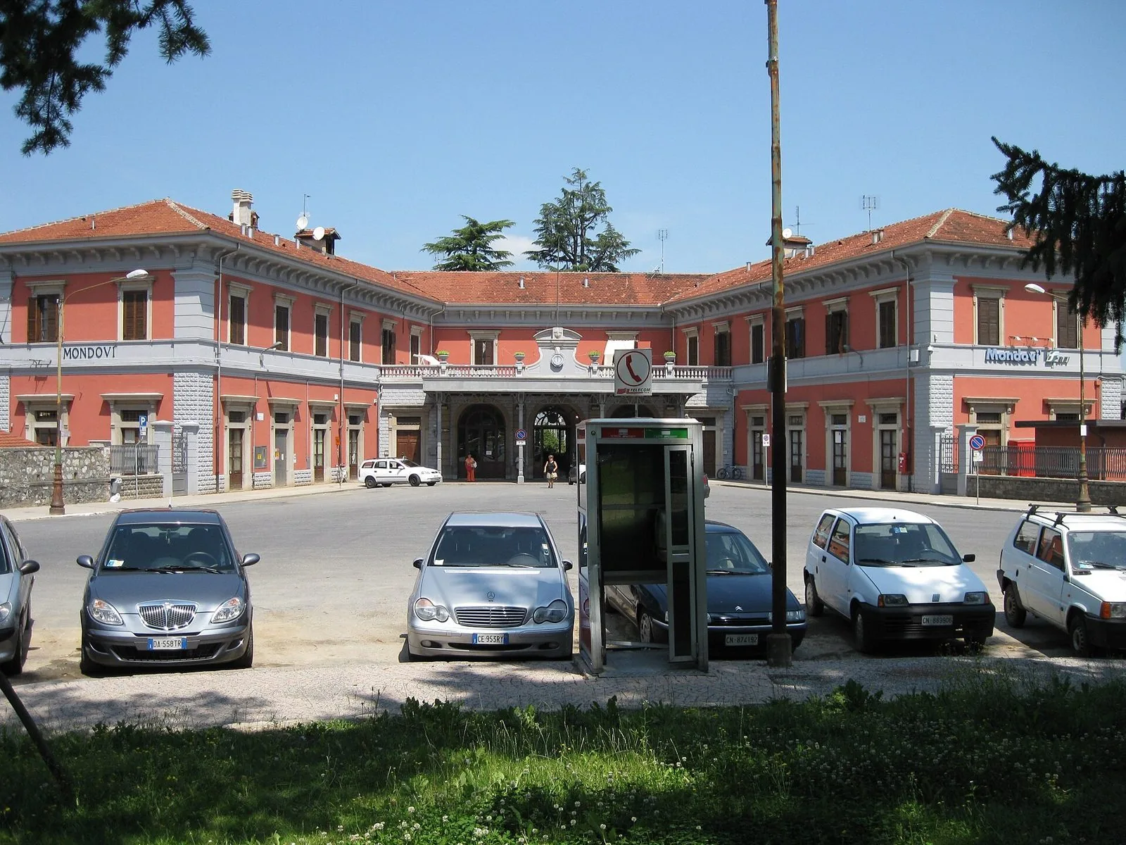La facciata rosa della stazione ferroviaria di Mondovì sotto un cielo azzurro
